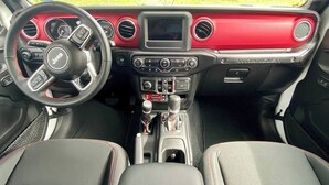 A vehicle interior with a steering wheel, dashboard, gear shift, and two front seats.