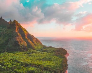 A coastal landscape with a prominent mountain, lush greenery, and a view of the ocean. - 2021 Jeep Wrangler Glamper Special (Anahola)
