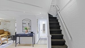 En modern inredning med ett skrivbord, en soffa, en trappa och en hall.