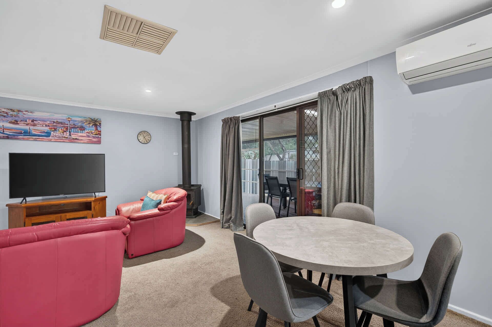 A living room with a sofa, TV, fireplace, dining table, and chairs.