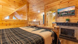 Een houten hutje interieur met een bed, een open haard en een prachtig uitzicht op een strand en reuzenrad.