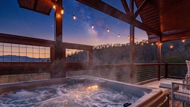 Een jacuzzi met uitzicht op de nachthemel en bergen.