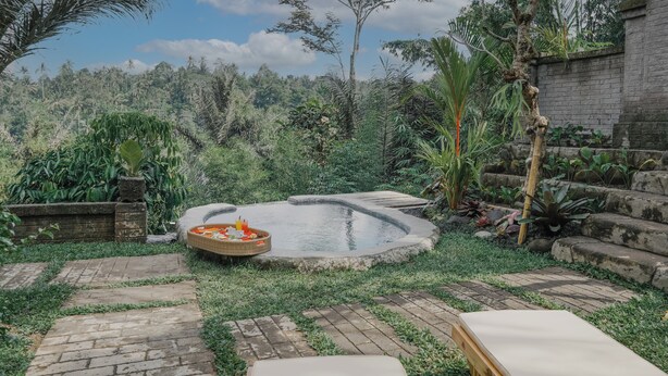 A garden with a small pool, stone steps, and a wicker basket with items.