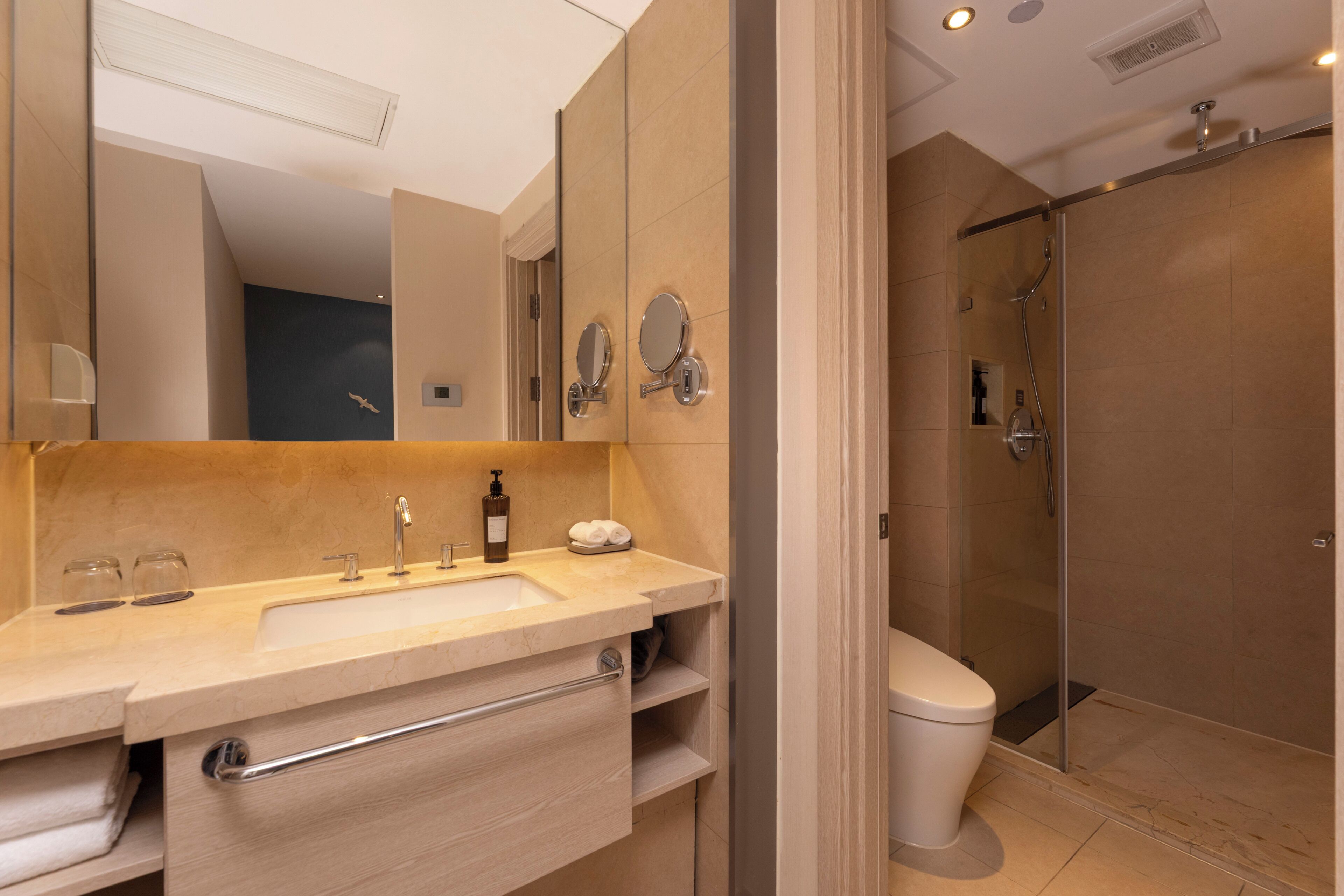 A modern bathroom with a sink, mirror, and shower.