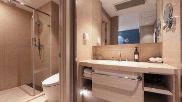A modern bathroom with a glass-enclosed shower, a toilet, a sink with a towel rack, and a mirror.