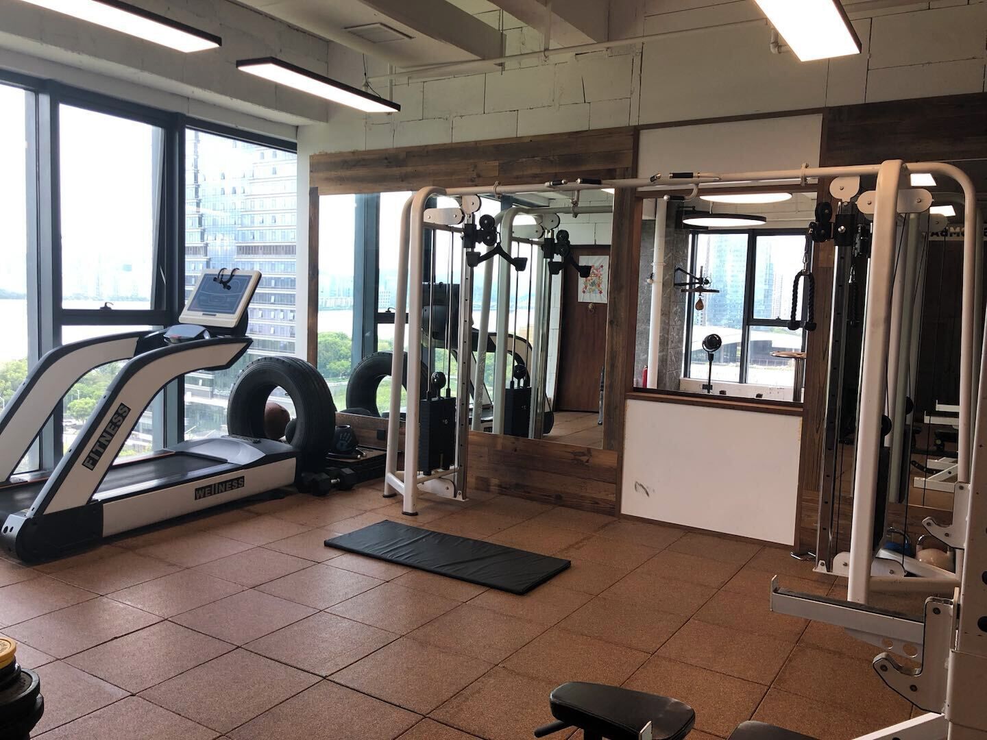 Un gimnasio con cinta de correr, máquinas de pesas y un espejo.