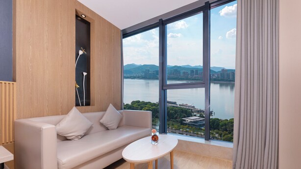 A modern room with a sofa, a small table, and a large window overlooking a body of water.
