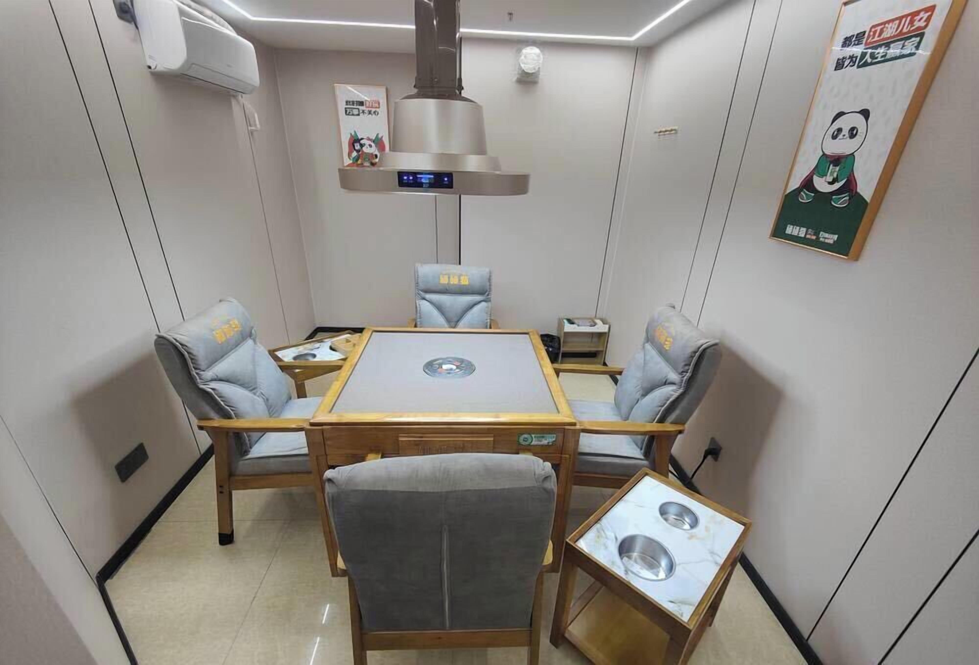 Un comedor con una mesa, sillas, una lámpara central y un cartel en la pared.