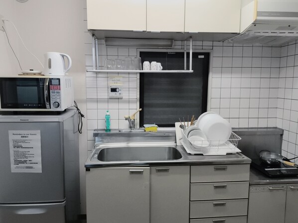 A kitchen with a microwave, sink, and dish rack. - Dc Sakura Hotel - Harmony Haven (Naniwa Ward, Osaka)