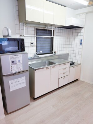 A kitchen with a microwave, refrigerator, sink, and cabinets. - Dc Sakura Hotel - Harmony Haven (Naniwa Ward, Osaka)
