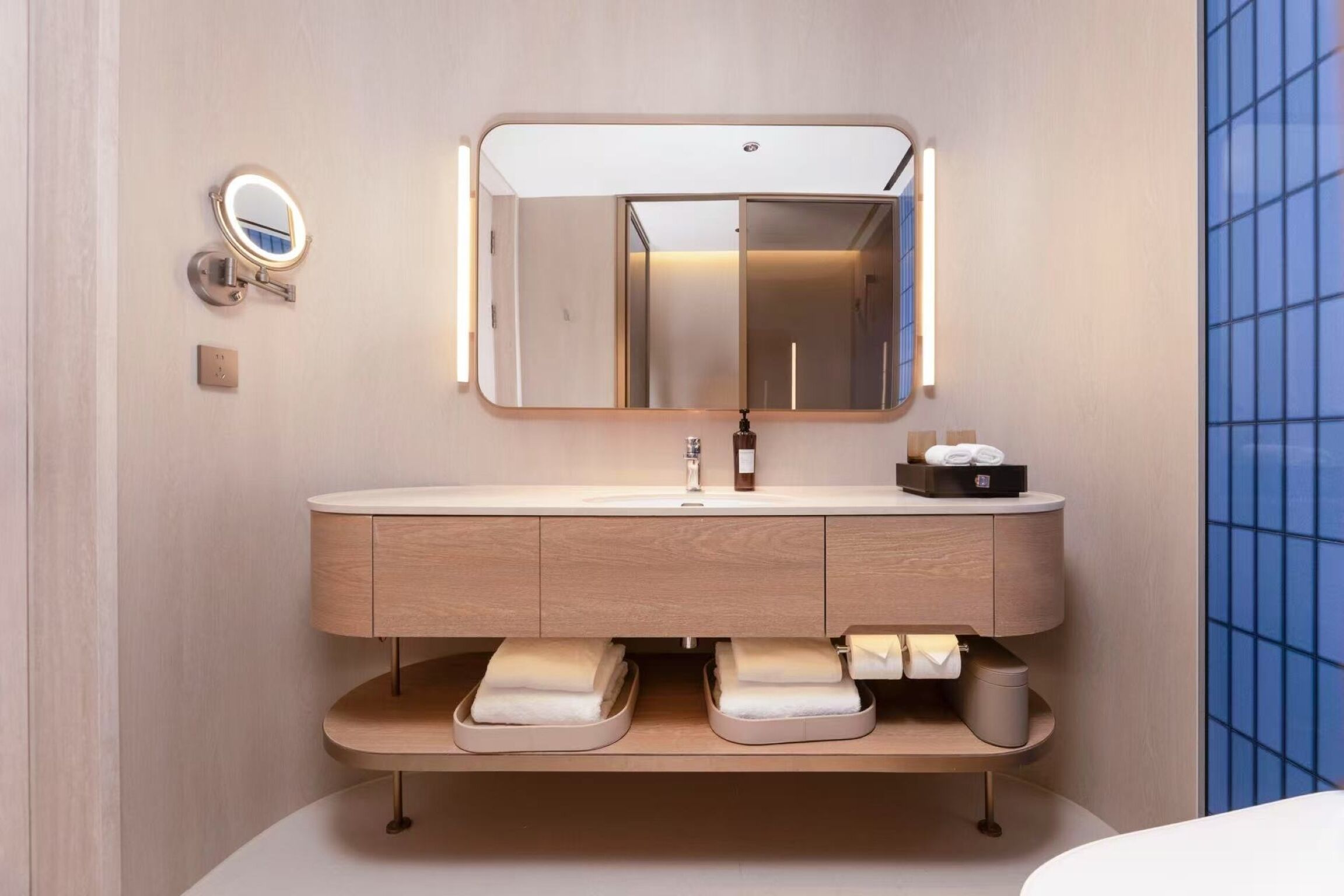 Un baño moderno con tocador, espejo y espacio para toallas.