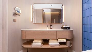 Un baño moderno con tocador, espejo y espacio para toallas.