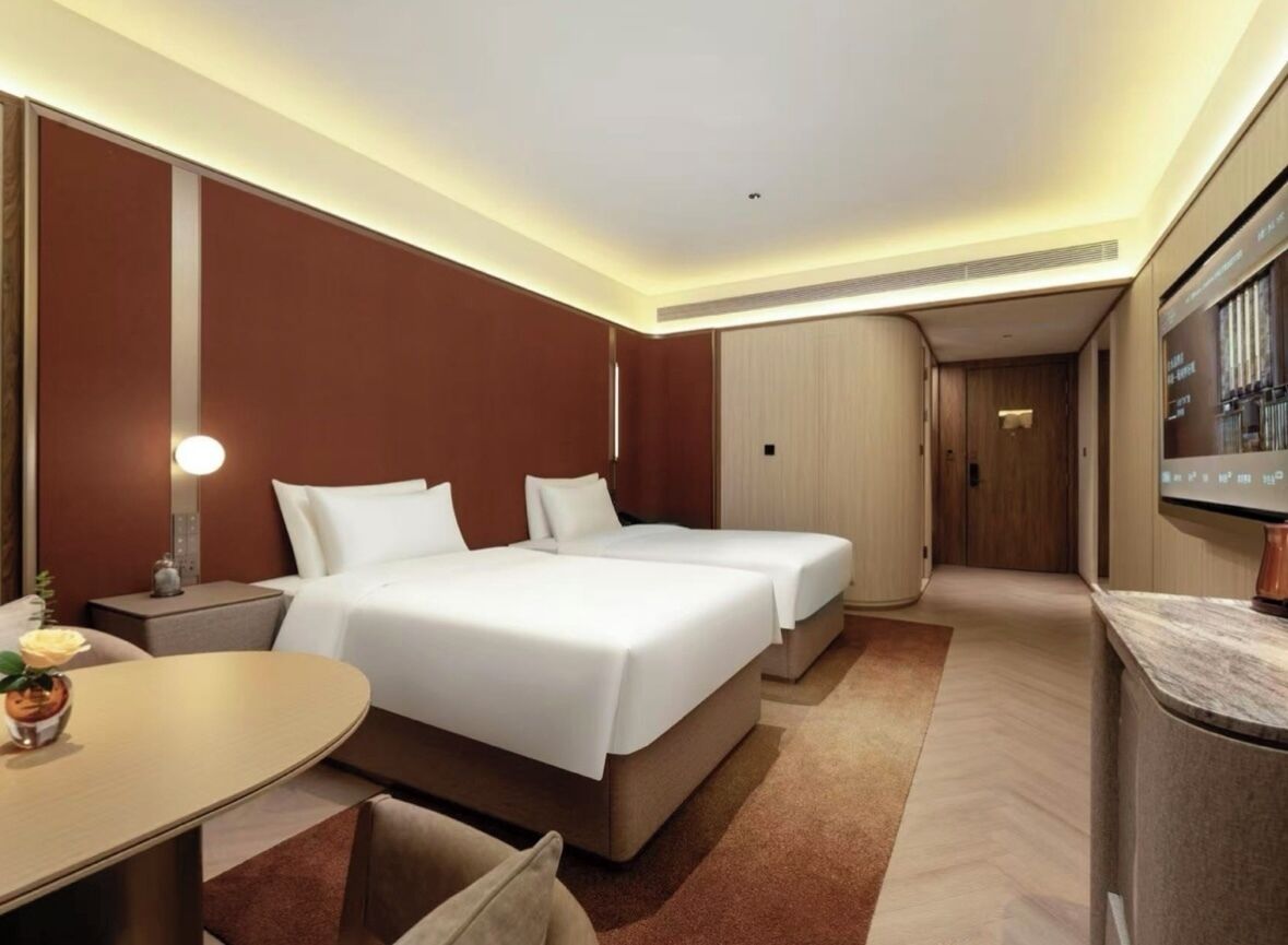 A hotel room with two beds, a desk, and a seating area.