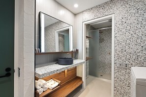 A modern bathroom with a granite countertop, a wooden vanity, a large mirror, and a shower area. - Geelong Conference Centre (Geelong)