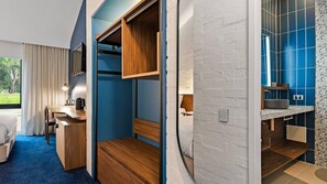Una habitación de hotel moderna con un escritorio de madera, una cama y un baño con azulejos azules.