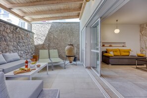 Ein moderner Außenbereich mit Steinwand, Holzboden und einer gemütlichen Sitzecke mit Kissen.