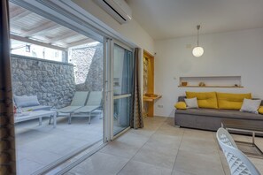 A modern living room with a sofa, a dining table, and a balcony with a stone wall. - Bougainvillea Old Town Apartment /w Terrace, Mali Lošinj, Croatia (Mali Lošinj)
