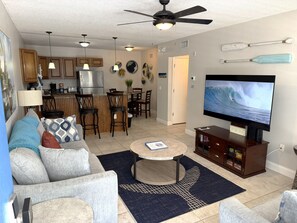 A living room with a television, sofa, coffee table, and kitchen area. - Sunny Sands in Cocoa Beach - Partial Oceanview (Cocoa Beach)