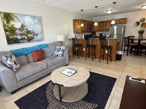 A compact living space with a kitchenette, a dining area, and a seating area with a sofa and coffee table. - Sunny Sands in Cocoa Beach - Partial Oceanview (Cocoa Beach)