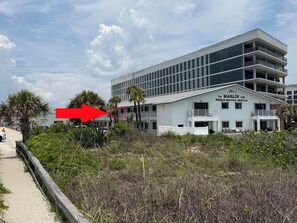 A modern building with balconies and a sign for weekly-monthly rentals. - Sunny Sands in Cocoa Beach - Partial Oceanview (Cocoa Beach)