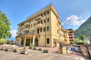 Ein mehrstöckiges Hotel mit Balkon, Außenbereich und einer Bergkulisse.
