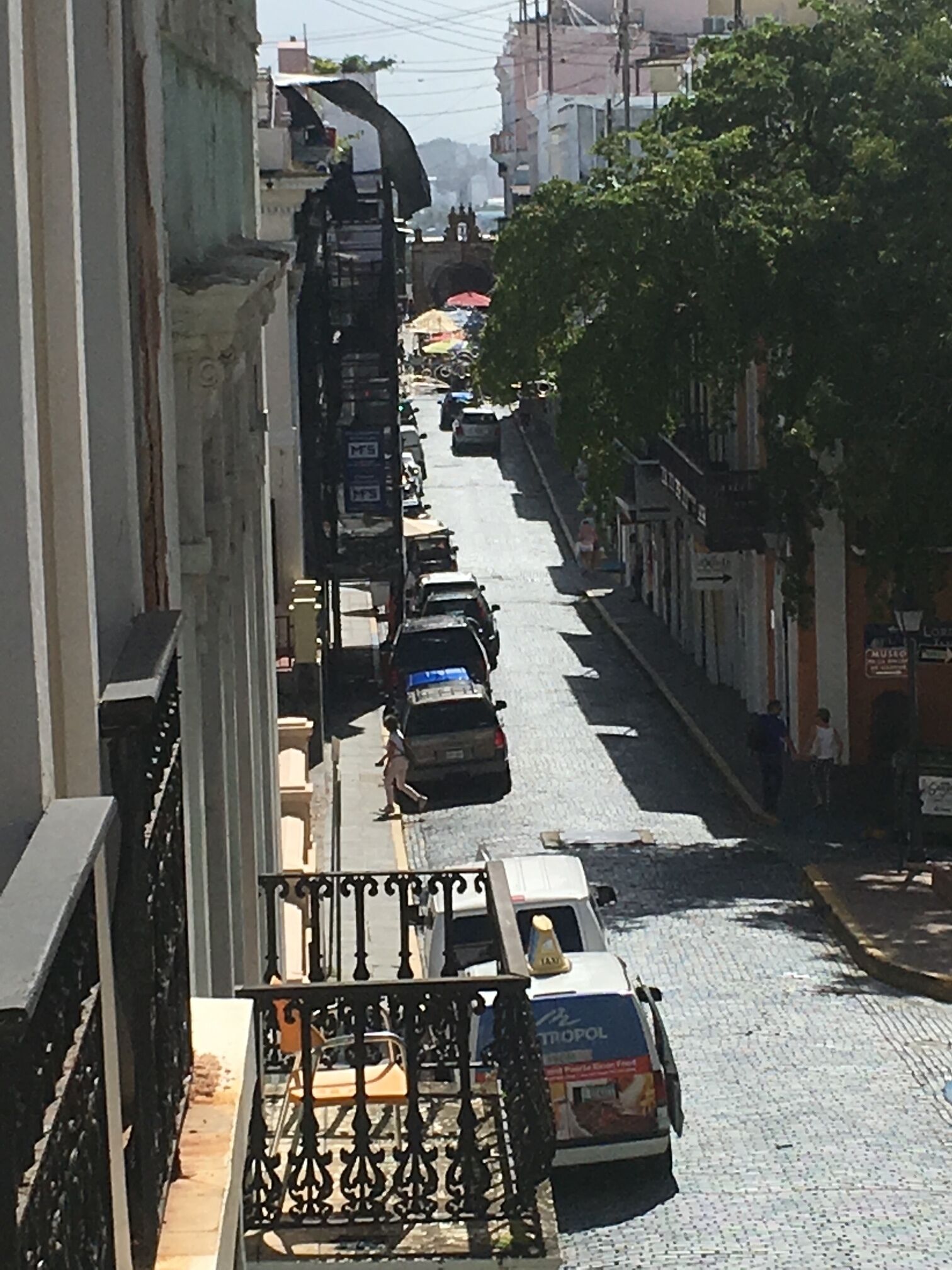 Une vue de rue avec des immeubles, des voitures garées et un piéton.
