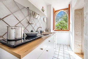 A kitchen with a stove, sink, and window with a view of greenery. - Casolare Di Puglia with private Pool, Noci, Italy (Noci)