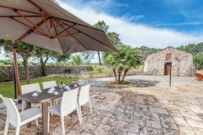 An outdoor patio with a table set for dining, surrounded by chairs, and a large umbrella providing shade. - Casolare Di Puglia with private Pool, Noci, Italy (Noci)