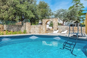 A swimming pool with a stone wall and a stone archway, surrounded by greenery. - Casolare Di Puglia with private Pool, Noci, Italy (Noci)