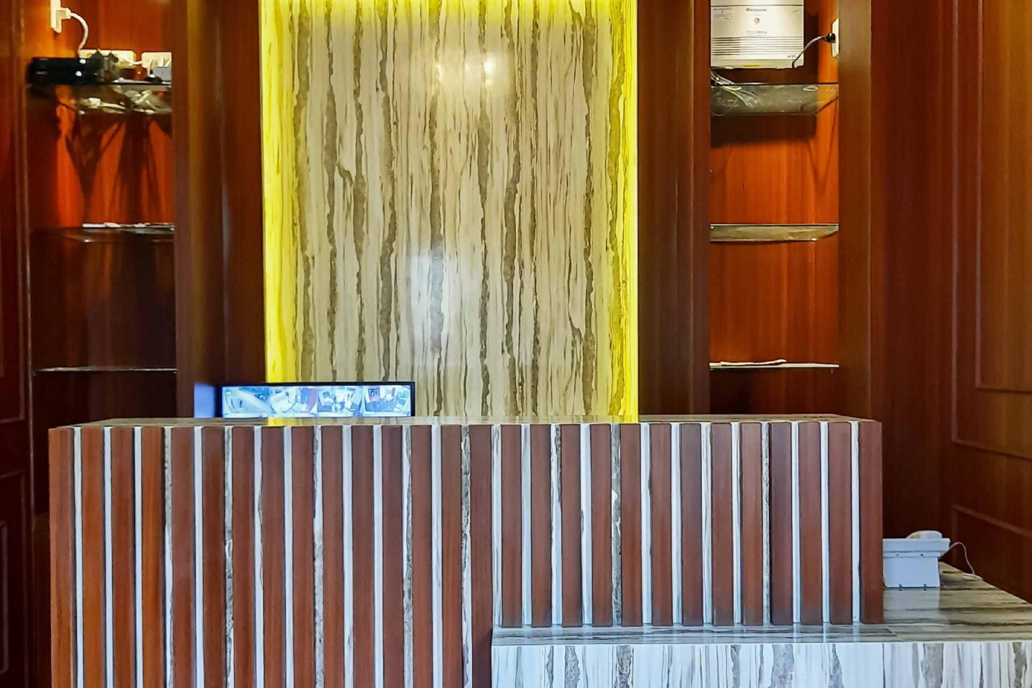 A reception desk with a vertical wooden panel design, a marble-topped counter, and a wall-mounted air conditioning unit.