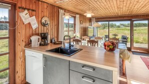 A wooden interior with a kitchen area, including a sink, cabinets, and a dining table with chairs. - "Satu" - 1.5km from the sea by Interhome (Løkken)
