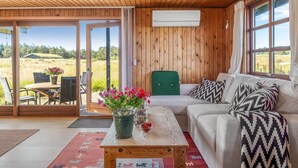 A room with wooden walls, a sofa, a table with a vase of flowers, and a view of the outdoors. - "Satu" - 1.5km from the sea by Interhome (Løkken)