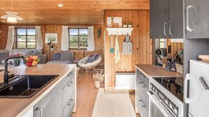 A modern kitchen with wooden walls, a central island, and a built-in oven. - "Satu" - 1.5km from the sea by Interhome (Løkken)