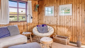A room with wooden walls, a sofa, a chair, a small table, and a window with curtains. - "Satu" - 1.5km from the sea by Interhome (Løkken)