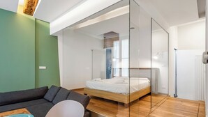 Une chambre moderne avec un lit, un canapé et une cloison en verre.
