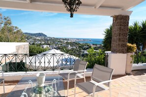 A terrace with a view of the sea, white chairs, a table with a vase, and a decorative column. - Villa San Francesco Garden (Forio d'Ischia)