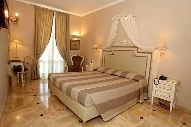 Una camera d'albergo con un letto grande, comodini, una scrivania e una sedia.