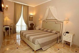 Una habitación de hotel con una cama grande, mesitas de noche, un escritorio y una silla.