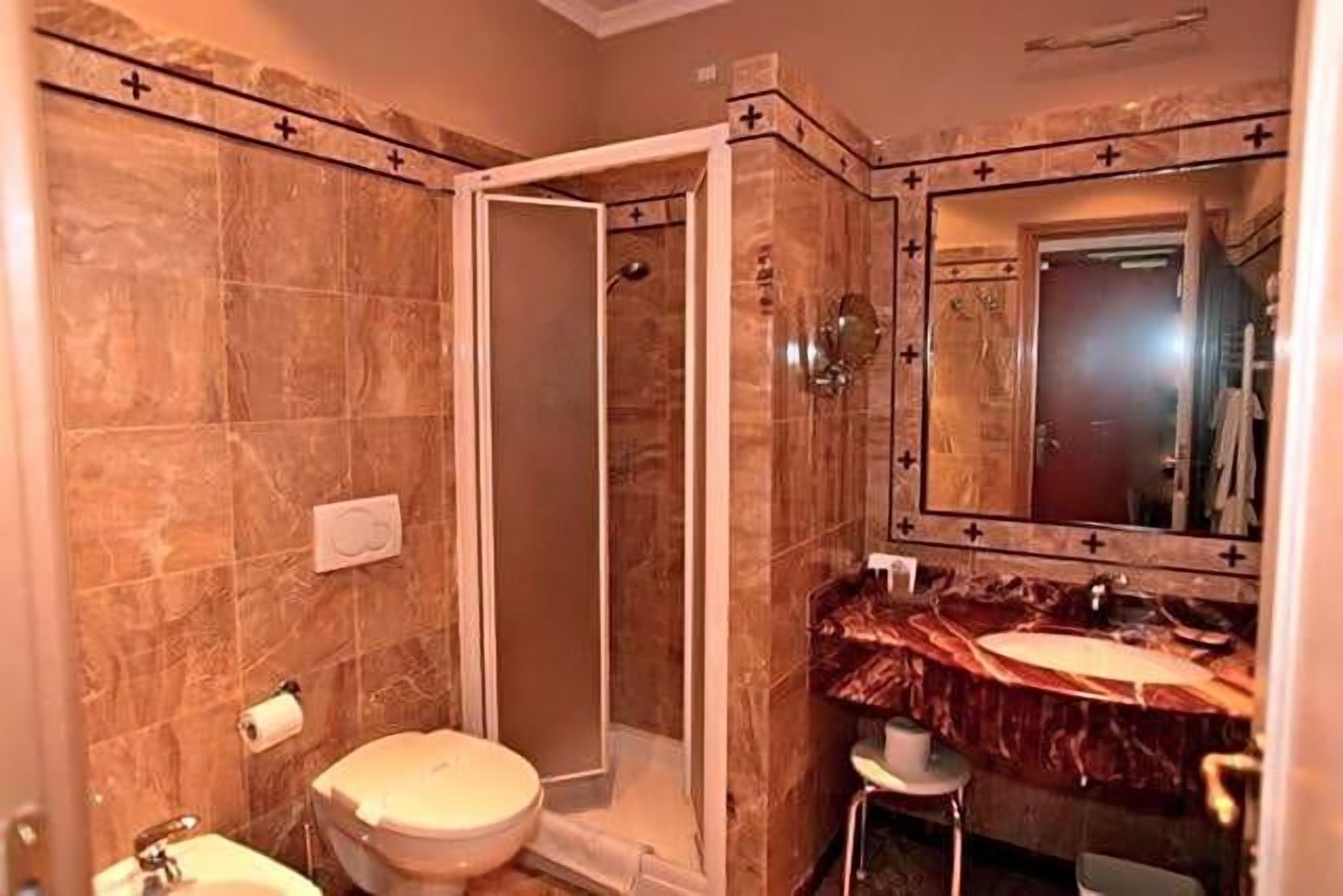 Un bagno con doccia, WC, lavandino e specchio.