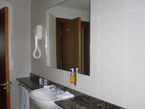 A bathroom with a white sink, a mirror, a towel, and a shower. - The Horse And Hound Inn Hotel (Ballynabola)