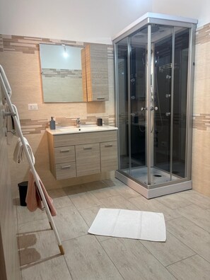Une salle de bain moderne avec une douche à parois de verre, un lavabo avec un miroir et un porte-serviettes.