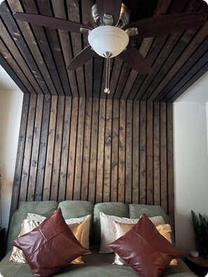 Una habitación con ventilador de techo, listones de madera y un sofá con cojines.