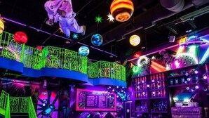 Zona de bar con luces de neón, barra y taburetes.