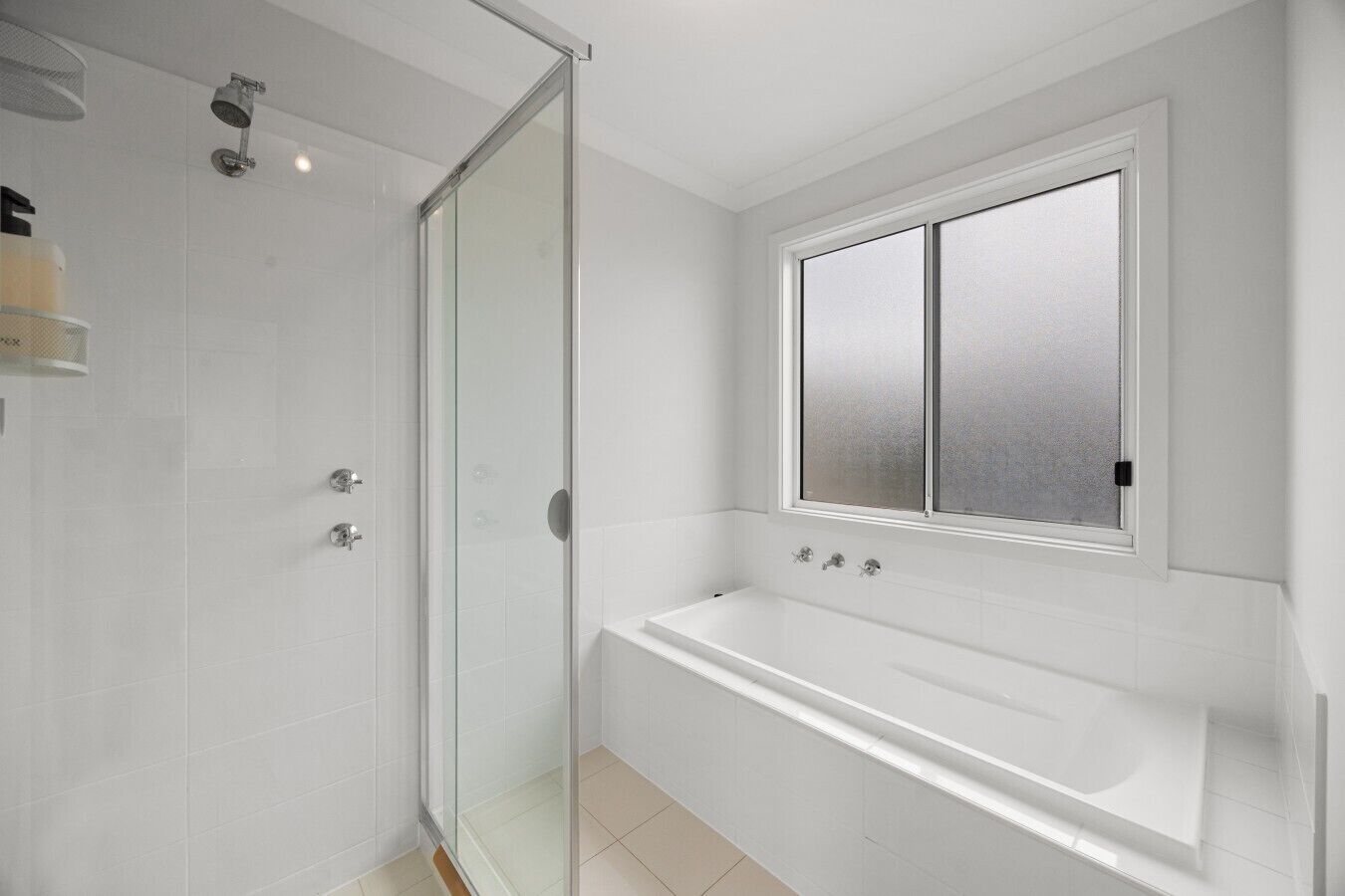 Un baño moderno con cabina de ducha de vidrio, bañera y ventana esmerilada.