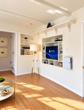 Un salon moderne avec un téléviseur à écran plat fixé au mur, un lampadaire sur trépied et une table basse en verre.