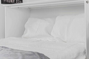 A white bed with a textured blanket and pillows, a white wall, and a sign above the bed. - 4BR Cottage • Relaxed Outdoor Living Near Expo (Sacramento)