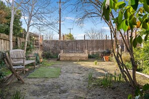 A backyard with a wooden bench, a garden hose, and a wooden fence. - 4BR Cottage • Relaxed Outdoor Living Near Expo (Sacramento)
