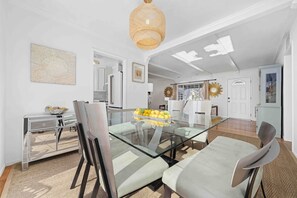 Un comedor moderno con una mesa de vidrio, sillas acolchadas y una lámpara decorativa en el techo.