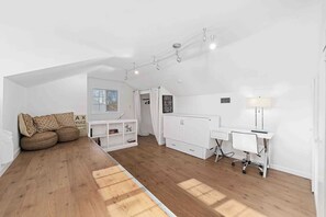 A modern loft bedroom with a sloped ceiling, a built-in desk, a radiator, and a large window. - 4BR Cottage • Relaxed Outdoor Living Near Expo (Sacramento)