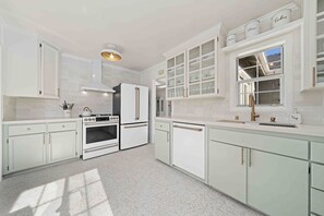 Una cocina moderna con armarios blancos, horno empotrado, refrigerador y ventana con vistas.